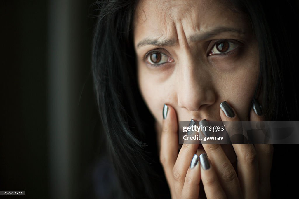 Worried Asian young woman putting her hand on mouth.