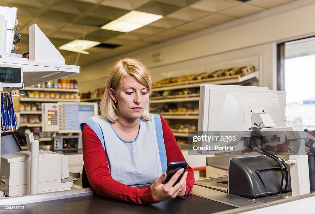 Worker using smart phone at counter in store