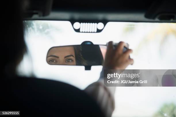 caucasian woman adjusting rear view mirror in car - car mirror stock-fotos und bilder