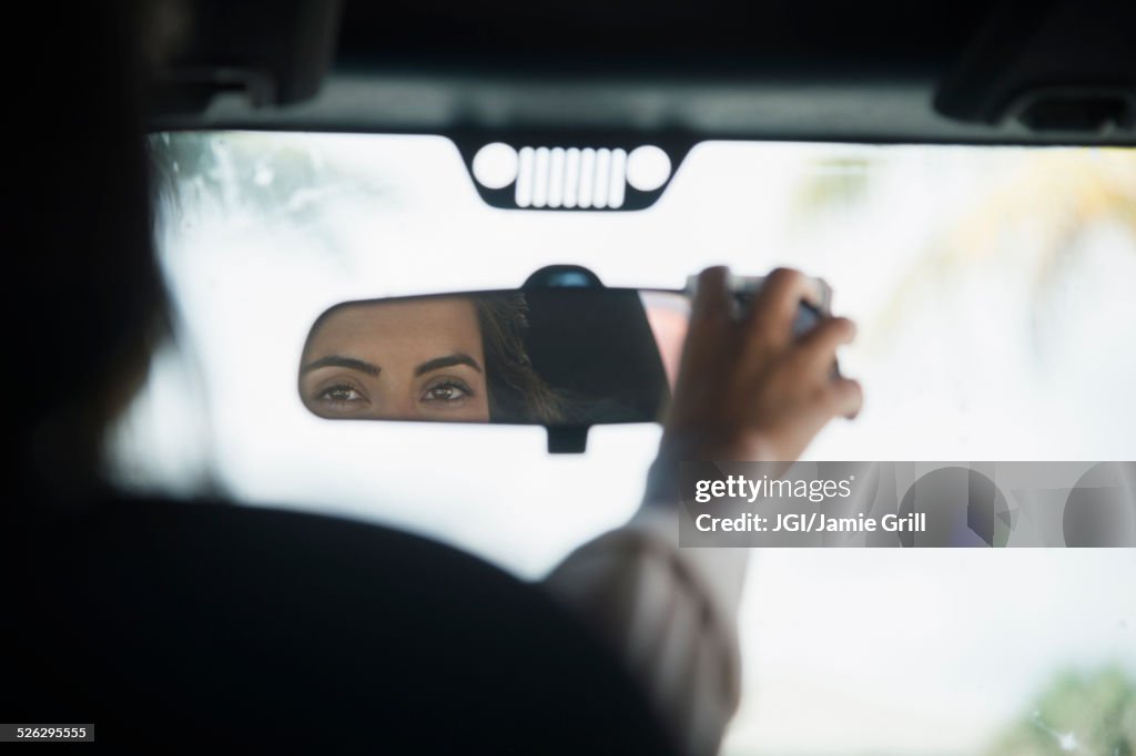 Caucasian woman adjusting rear view mirror in car