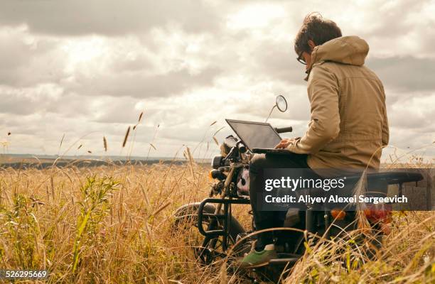 mari man using laptop on motorcycle in rural field - reading glasses isolated stock pictures, royalty-free photos & images