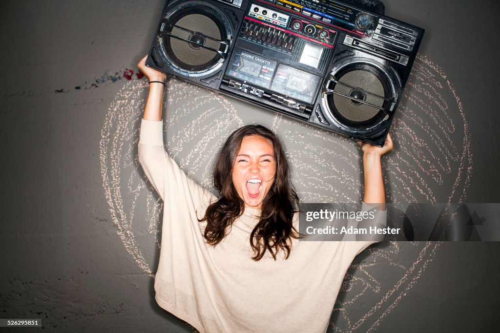 Caucasian woman holding boom box near chalk heart on wall