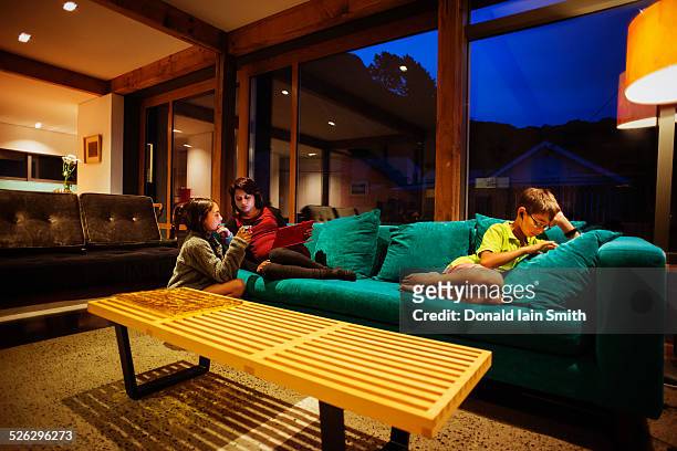 mother and children relaxing together in modern living room - indian living room stock-fotos und bilder