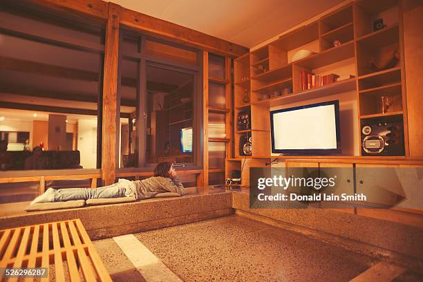 mixed race girl watching television in modern living room - luxury home movie theater stock pictures, royalty-free photos & images
