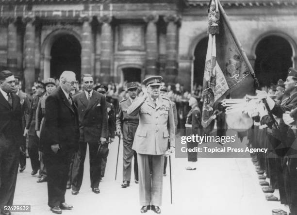 British statesman Winston Churchill salutes the guard of honour before recieving the medaille Militaire from French Prime Minister Paul Ramadier at a...
