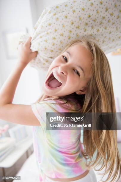 caucasian girl having pillow fight in bedroom - pillow fight stock pictures, royalty-free photos & images
