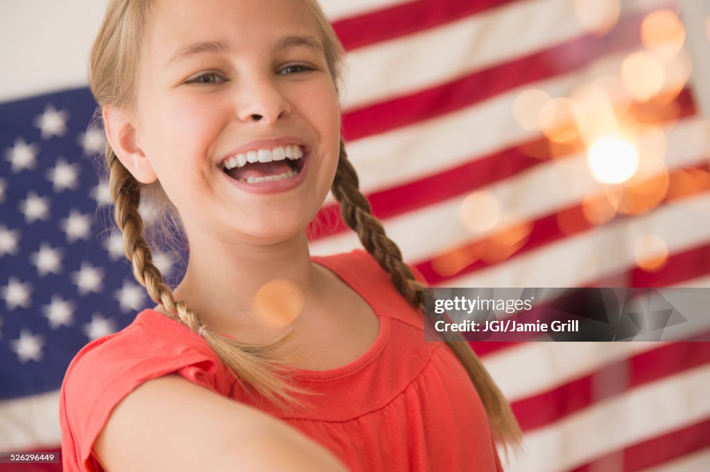 Caucasian girl holding sparkler by American flag