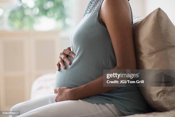 pregnant african american mother holding her stomach - human abdomen foto e immagini stock