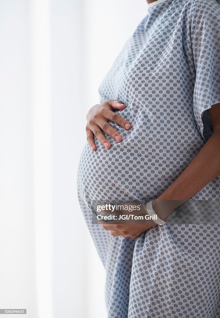 Pregnant African American mother holding her belly in hospital