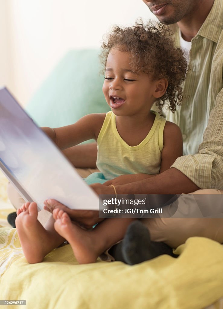 Father and daughter reading book on bed