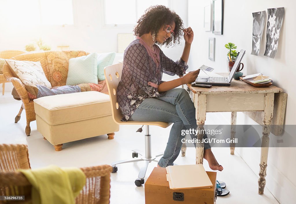 Mixed race woman using laptop in living room