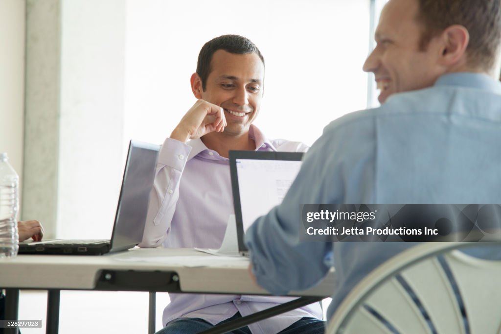 Businessmen using laptop computers in meeting