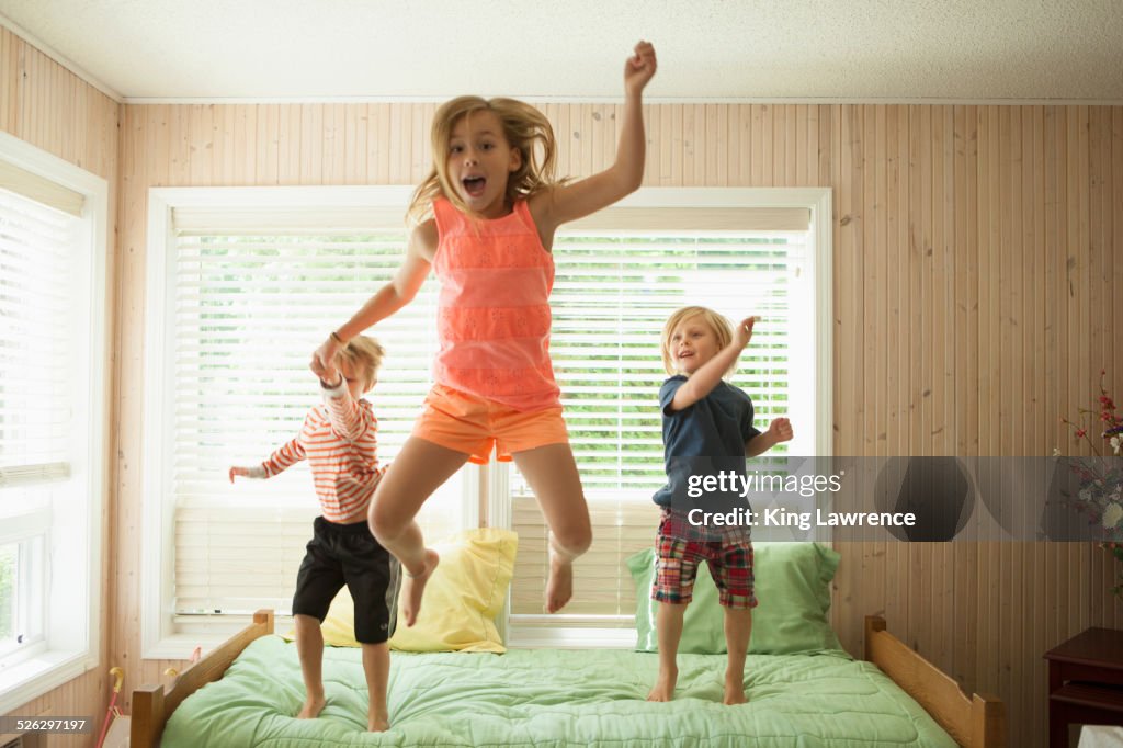 Caucasian children jumping on bed