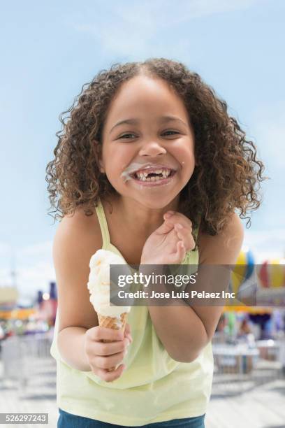 mixed race girl eating ice cream cone outdoors - girl eating messy ice cream cone stock pictures, royalty-free photos & images