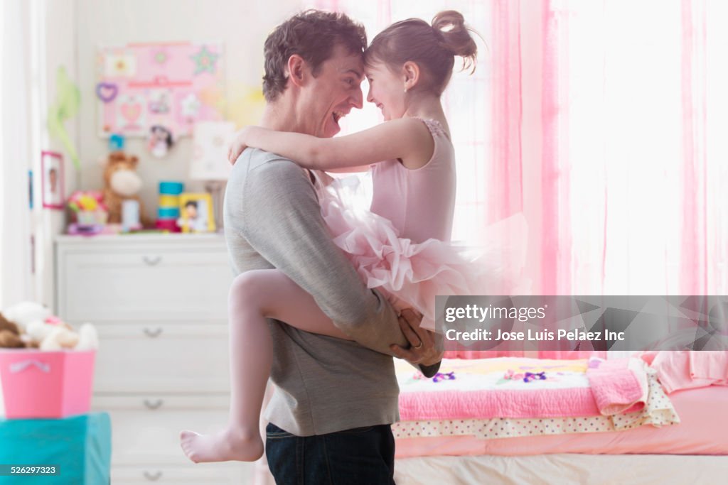 Caucasian father and daughter hugging in bedroom