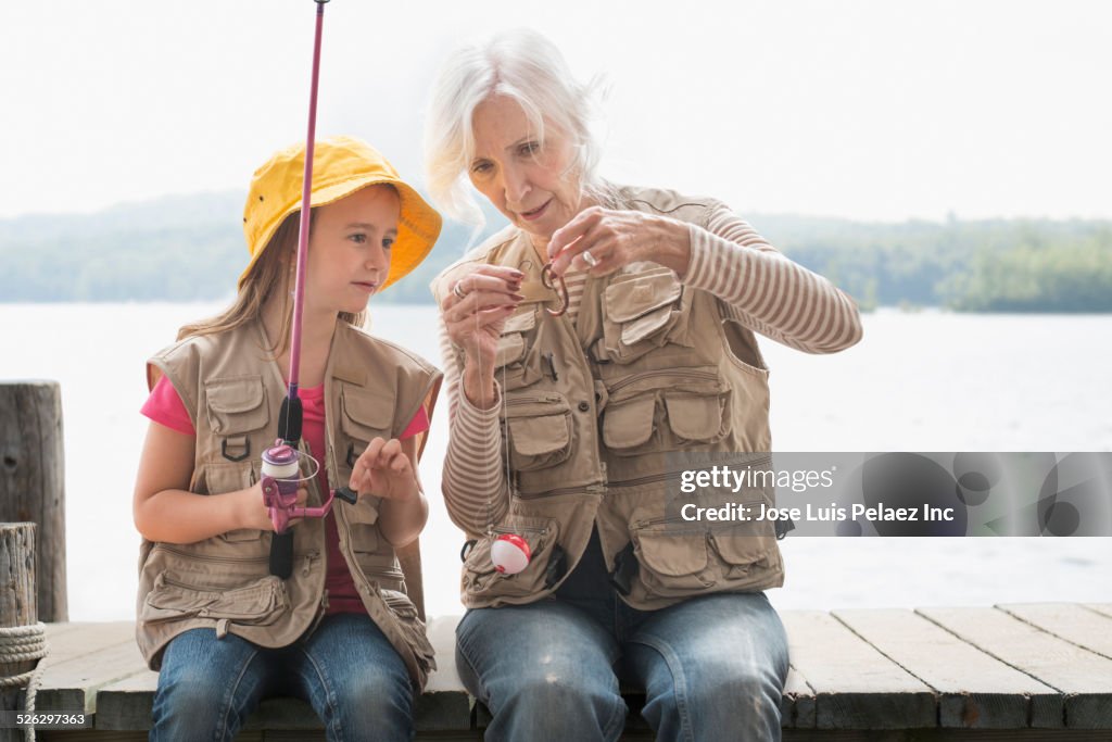 Caucasian grandmother and granddaughter fishing at lake