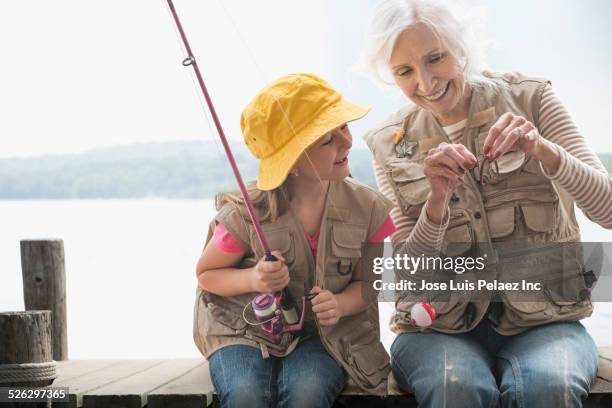 caucasian grandmother and granddaughter fishing at lake - fishing hook worm stock pictures, royalty-free photos & images