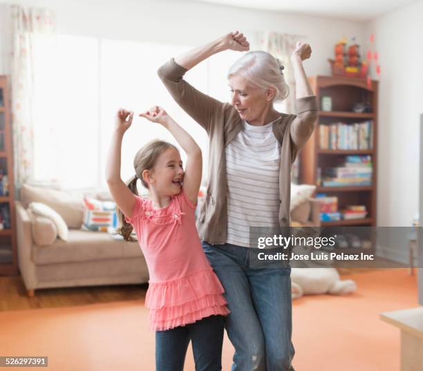 caucasian grandmother and granddaughter dancing in living room - granddaughter ストックフォトと画像