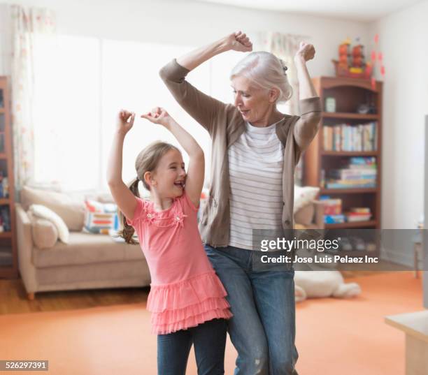 caucasian grandmother and granddaughter dancing in living room - old woman dancing bildbanksfoton och bilder