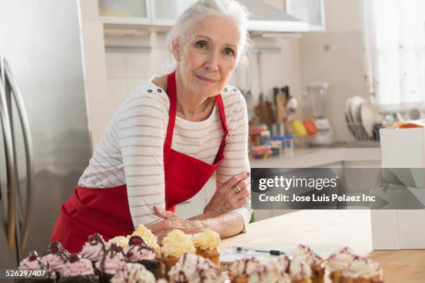 older caucasian woman with cupcakes in kitchen - woman back stock-fotos und bilder