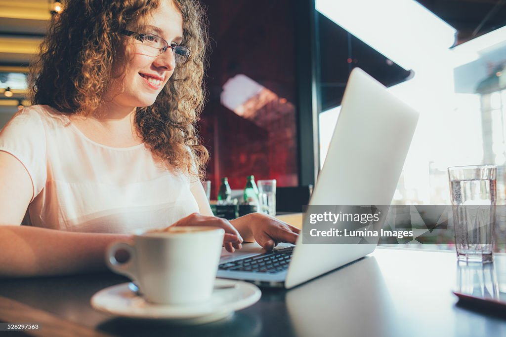 Woman using laptop computer in cafe