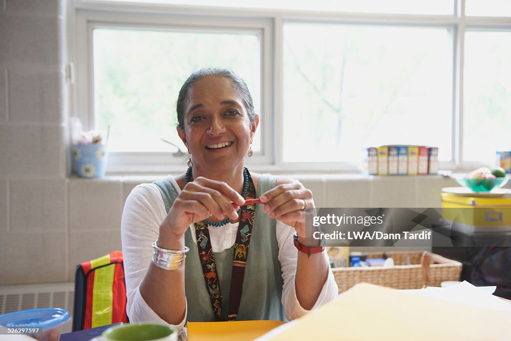 Indian teacher smiling at desk in classroom