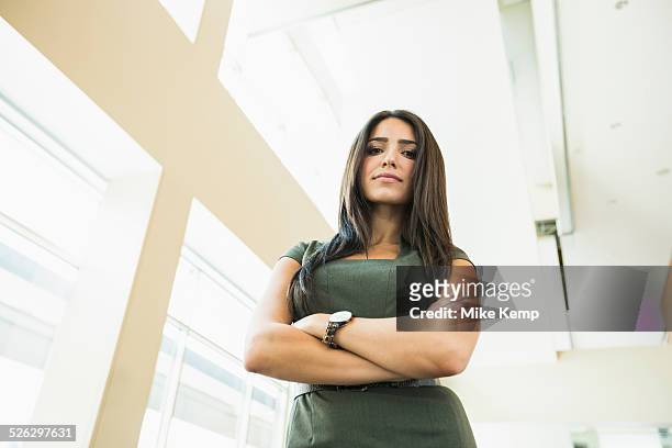low angle view of hispanic businesswoman standing in office - low angle view stock pictures, royalty-free photos & images