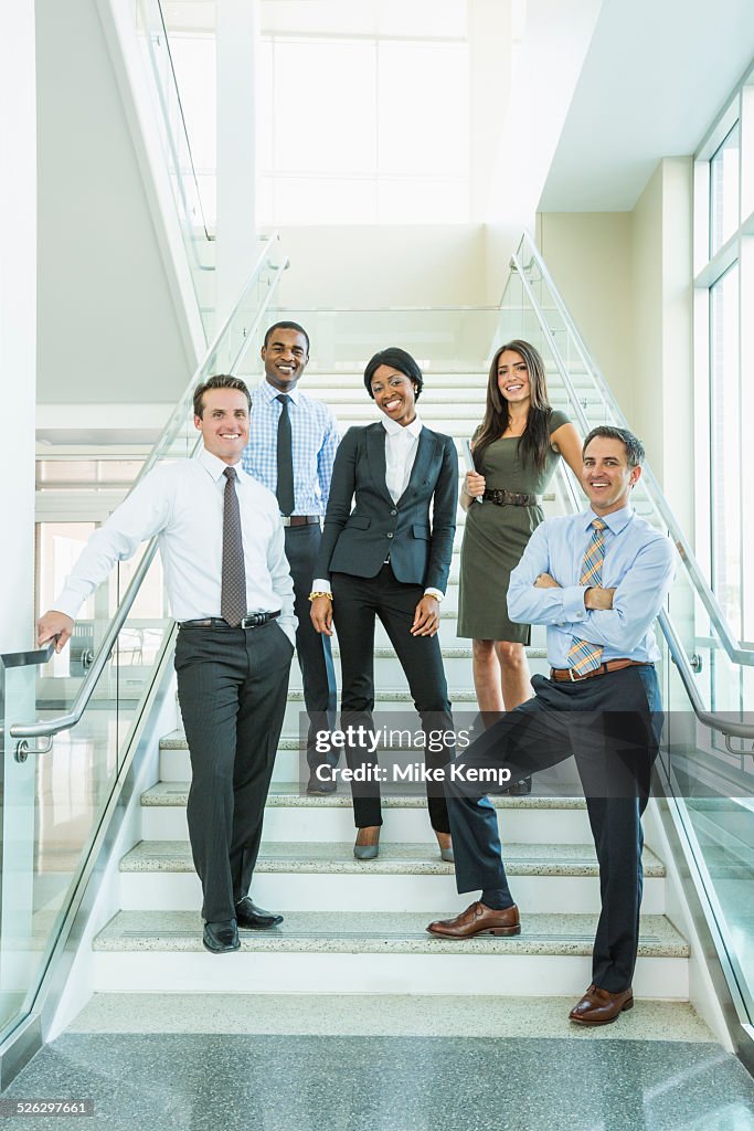Business people smiling on office staircase