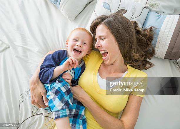 caucasian mother and son playing on bed - kietelen stockfoto's en -beelden