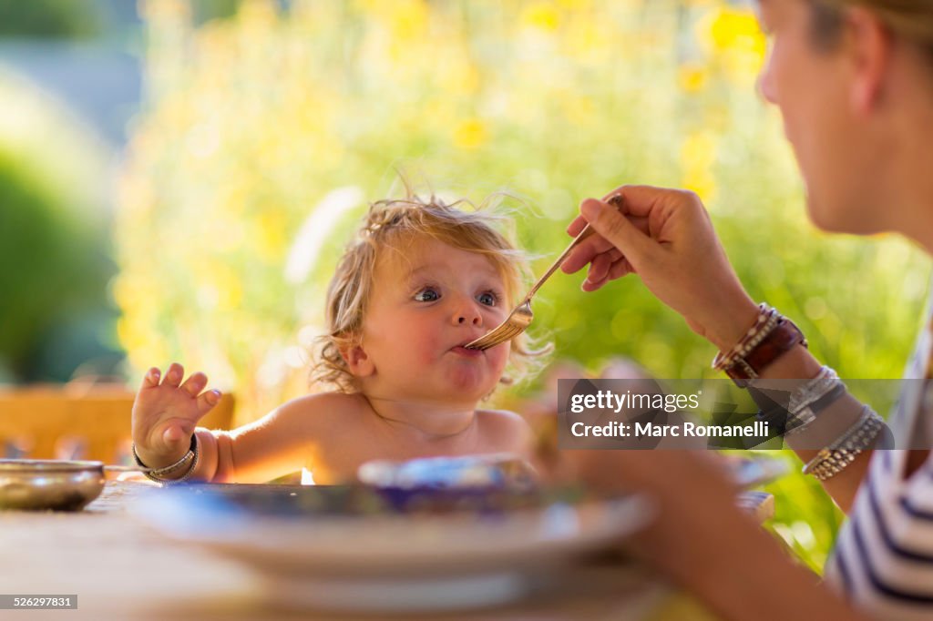 Caucasian mother feeding baby son at table