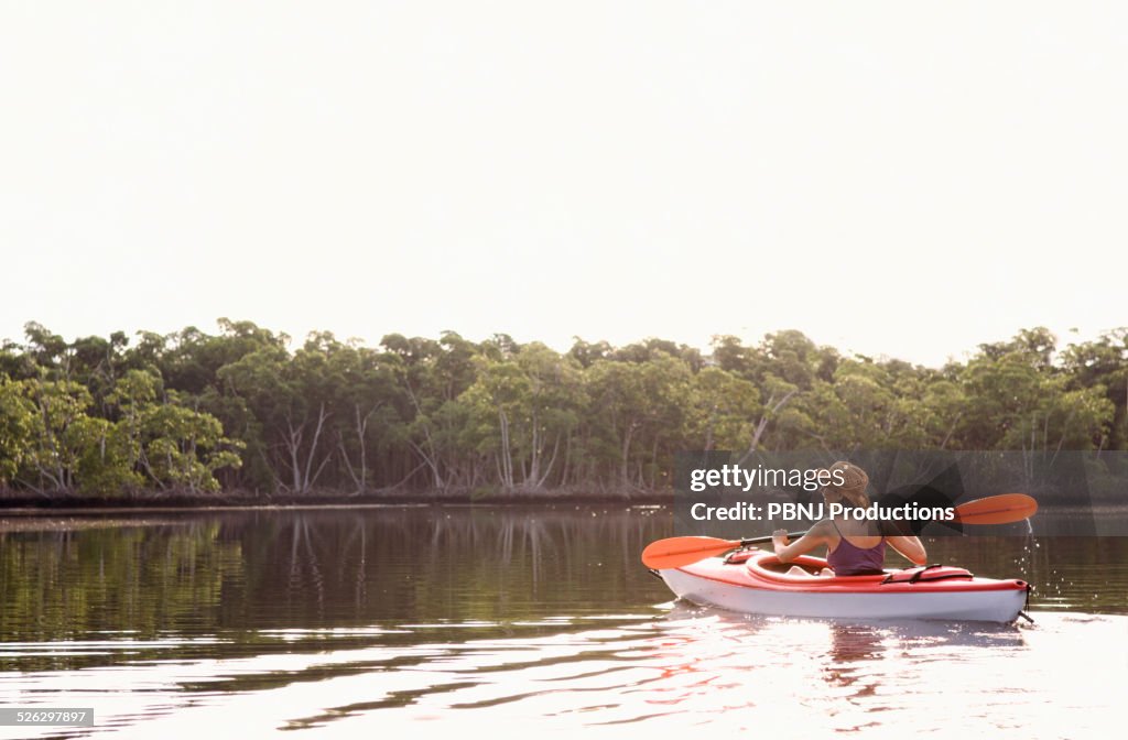 Mixed race woman kayaking in lake