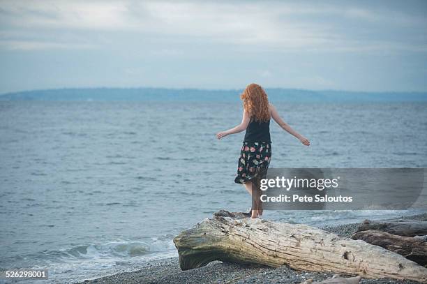 girl walking on driftwood on beach - barefoot redhead ストックフォトと画像