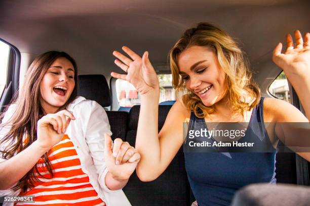 caucasian teenage girls dancing in back seat of car - woman front and back stock-fotos und bilder