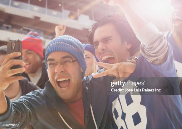 fans taking cell phone picture at american football game - mates celebrating stock pictures, royalty-free photos & images