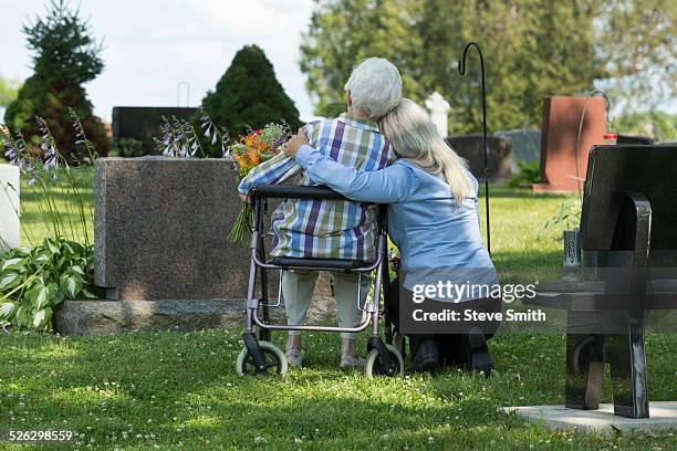caucasian mother and daughter visiting grave in cemetery - cemetery stock pictures, royalty-free photos & images