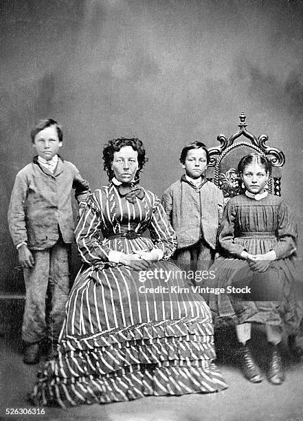 Mother and her three children sit for a tintype portrait.