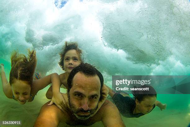 father swimming underwater in the ocean with three children - family with three children stock pictures, royalty-free photos & images