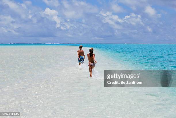 two children running on sandbar in ocean, aitutaki, cook islands - cook islands stock pictures, royalty-free photos & images