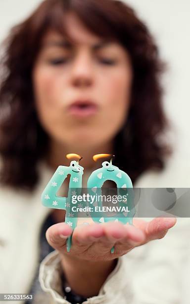 woman blowing out candles for 40th birthday - 40 birthday foto e immagini stock