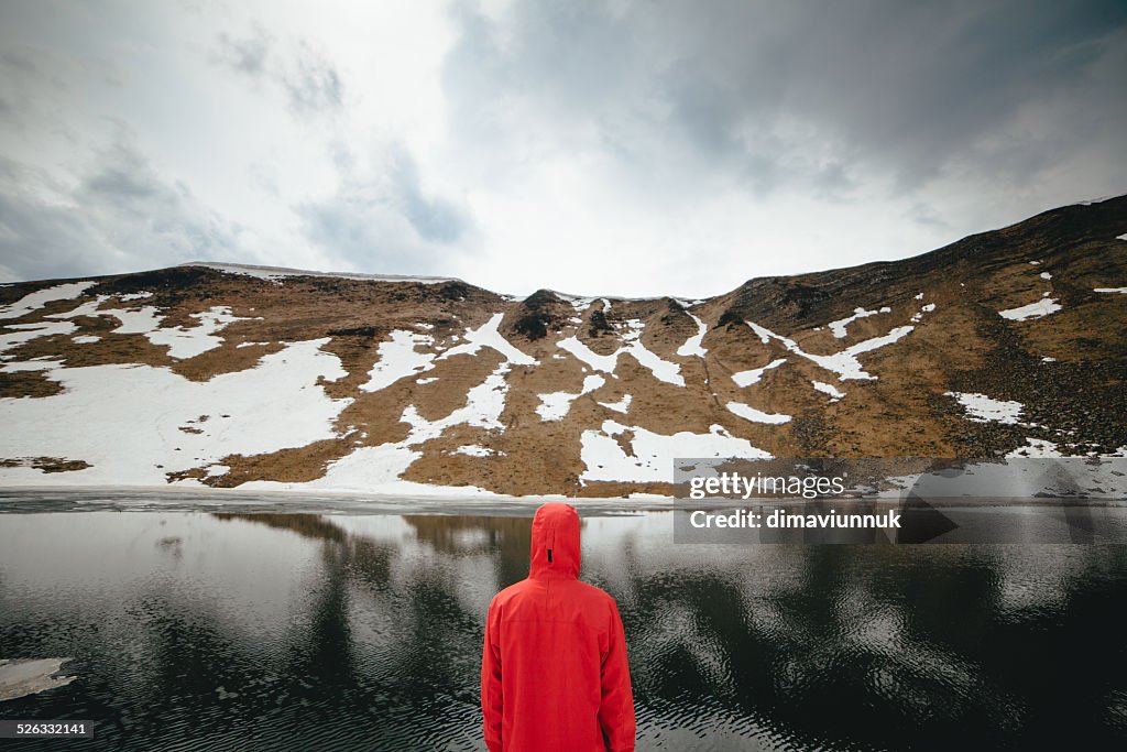 Back view of young man looking at mountain lake