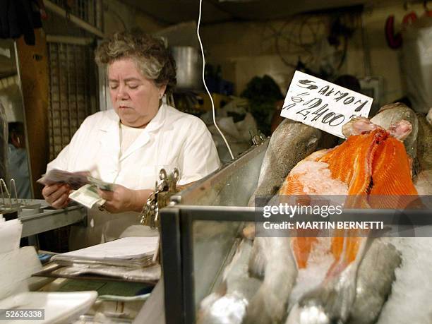 La cajera de un puesto de pescado que vende salmon chileno cuenta dinero en el mercado central de Santiago el 15 de abril de 2005. Chile rechazo esta...