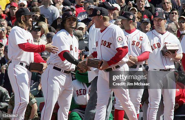 Curt Schilling of the Boston Red Sox makes his way down the line as he shakes hands with teammates Manny Ramirez and Johnny Damon after Bostons World...