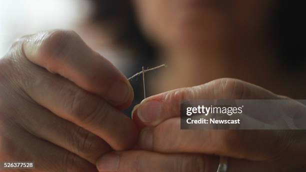 Putting thread through a needle.