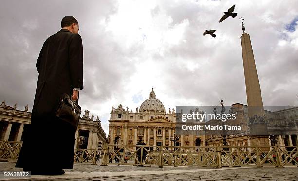 Priest stands in Saint Peter's Square as birds fly overhead April 16, 2005 in Vatican City. Cardinals under the age of 80 will start the conclave...