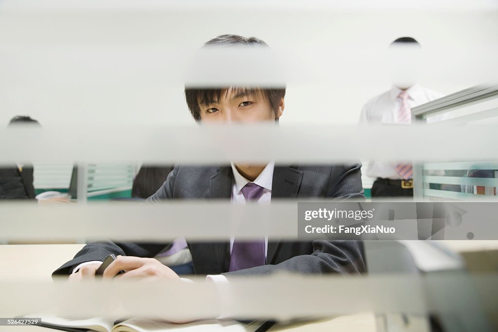 Businessman in office, view through window blinds