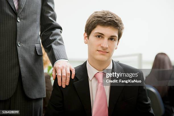 man sitting in office with boss behind him - persuasion stock pictures, royalty-free photos & images