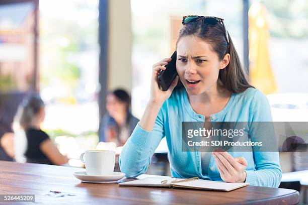 woman making angry phone call in local coffee shop - rage stockfoto's en -beelden