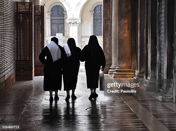 three religious sisters walking in venice - nonne stock-fotos und bilder