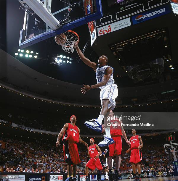 Dwight Howard of the Orlando Magic makes a slam dunk against Rafer Alston of the Toronto Raptors at TD Waterhouse on March 30, 2005 in...