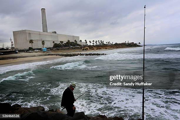 Man fishes along a jetty with the Carlsbad Desalination plant in back in Carlsbad, CA on Monday, June 3, 2013. San Diego is spending $1 billion to...